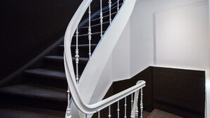 Una escalera moderna con balaustres blancos y un rellano alfombrado oscuro.