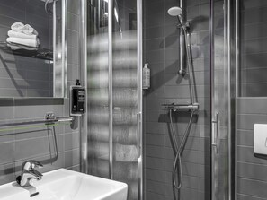 Ein modernes Badezimmer mit Duschkabine aus Glas, Waschbecken und Handtuchhalter.