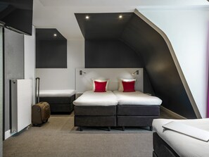 A modern hotel room with a loft bed, a small desk, a suitcase, and a radiator. - ibis Styles Amsterdam Amstel (Amsterdam)