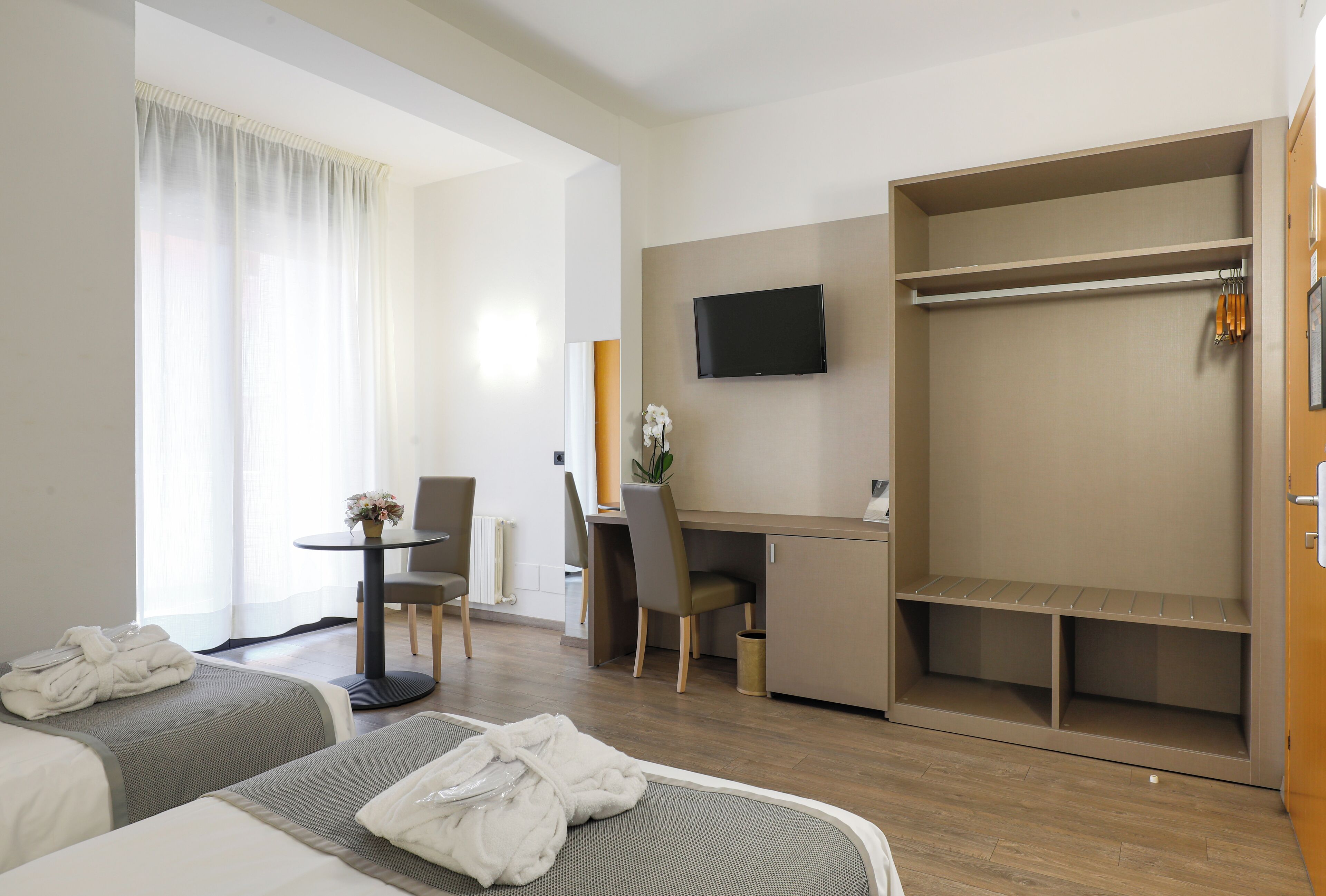 Una habitación de hotel con dos camas, un escritorio, un televisor y un armario.