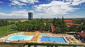Un complejo turístico con varias piscinas, tumbonas y una amplia zona arbolada.