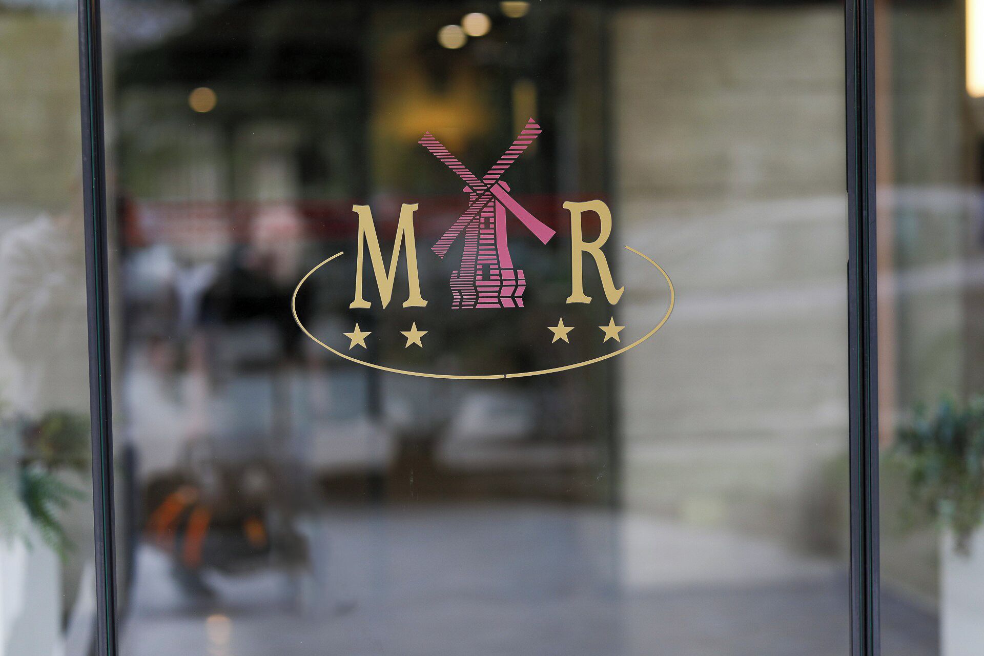 A logo with 'M' and 'R' letters, a windmill, and three stars on a glass window.