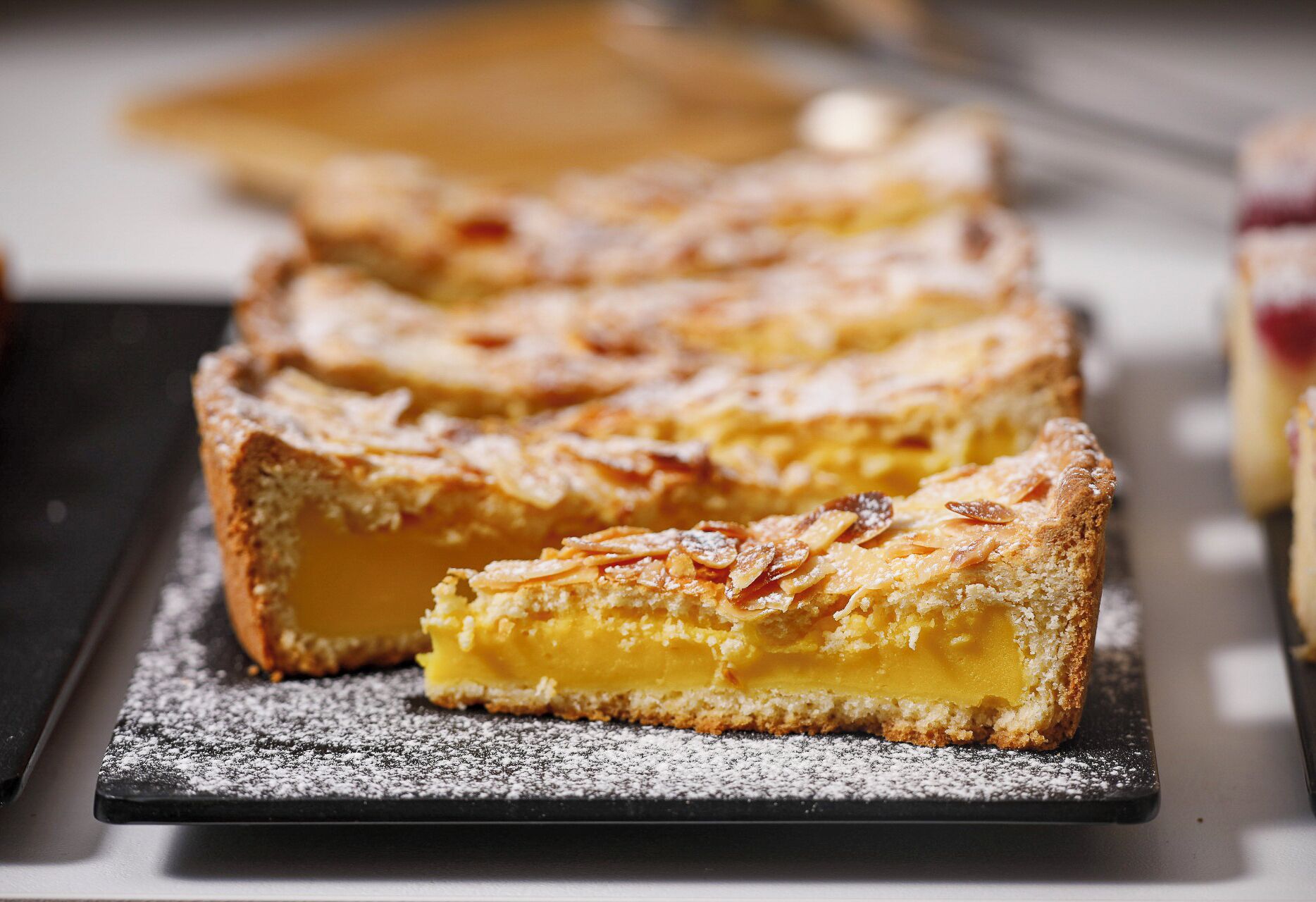 Uma sobremesa com crosta crocante e recheio cremoso, polvilhada com açúcar de confeiteiro.