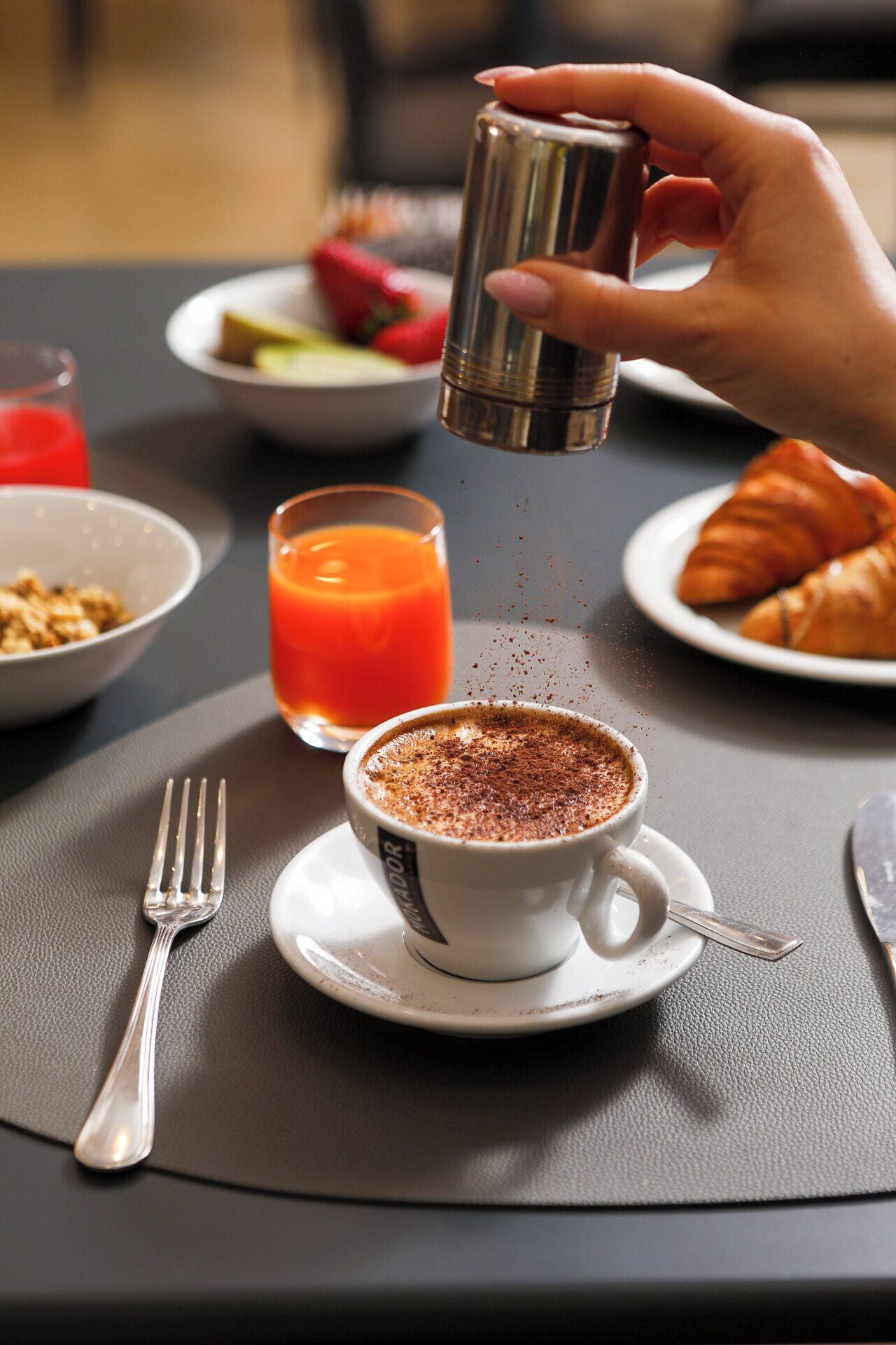 A breakfast setting with a cup of coffee, a glass of orange juice, and croissants on a table.
