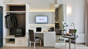 Una habitación de hotel moderna con escritorio, ordenador y televisión mostrando la palabra “WELCOME”.