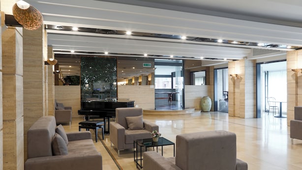 Un amplio hall con un piano, sofás y un gran jarrón decorativo.