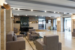 A spacious lobby with a piano, sofas, and a large decorative vase.