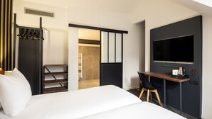 A modern hotel room with a bed, a desk, a chair, a TV, and a wardrobe. - Aris Grand-Place Hotel (Brussels)