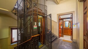 A multi-level interior with a metal staircase, wooden doors, and a view into a room with a bar area. - Lilium Hotel (Florence)