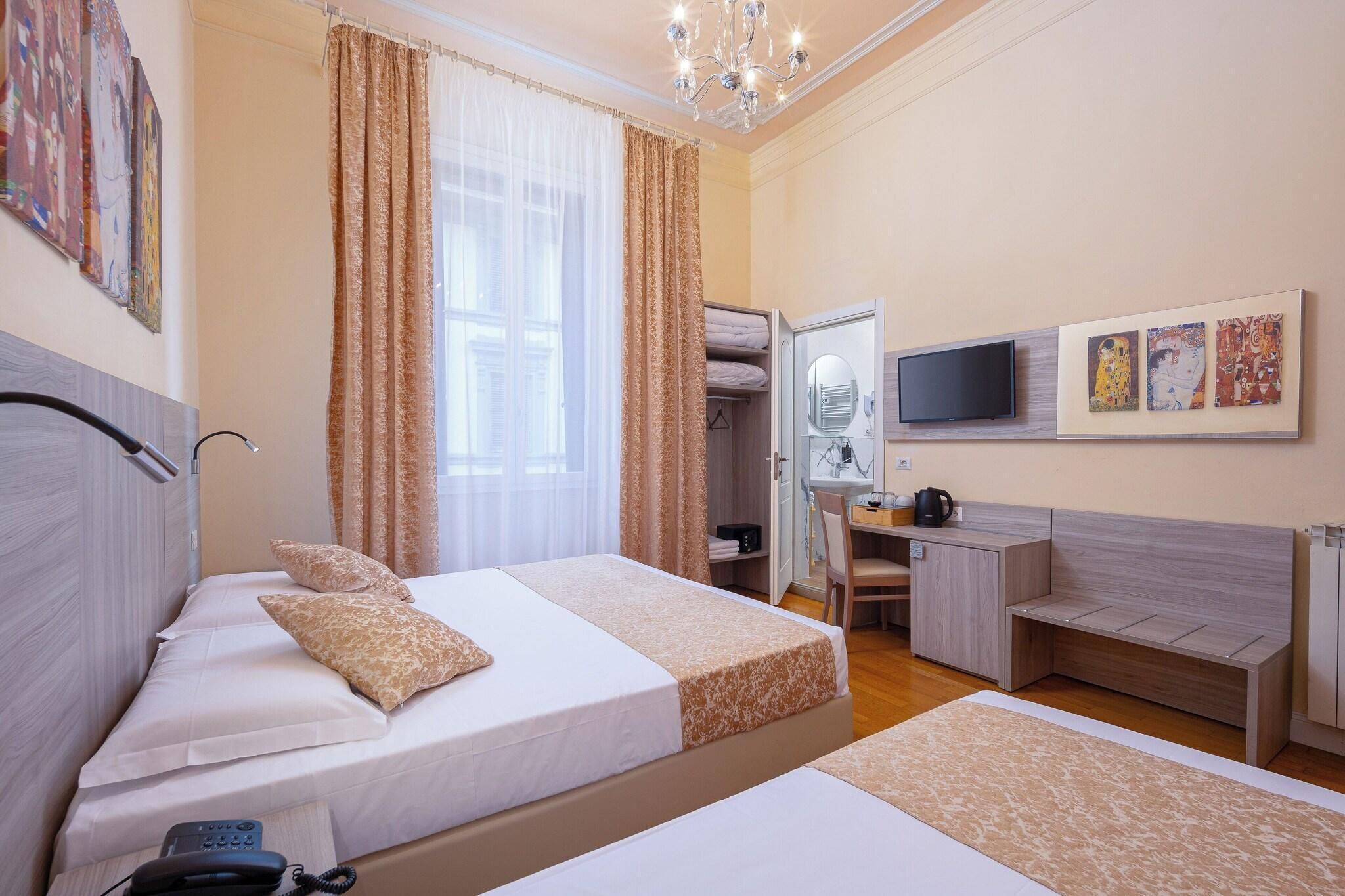 A hotel room with a bed, bedside table, desk, chair, and a TV mounted on the wall.