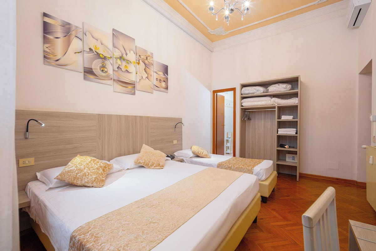 Una habitación de hotel con dos camas, un armario y obras de arte en la pared.