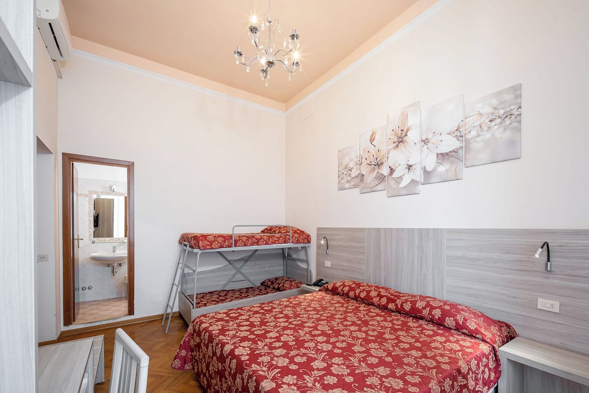 Un dormitorio con literas, un candelabro, un lavabo y obras de arte en la pared.