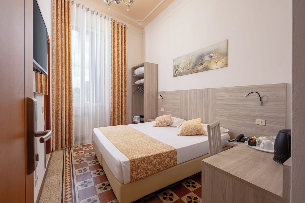 Una habitación de hotel con cama, mesita de noche y un cuadro en la pared.