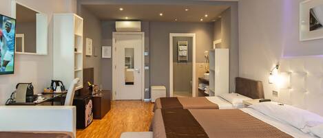 Una habitación de hotel con cama, escritorio, silla, televisor y baño.