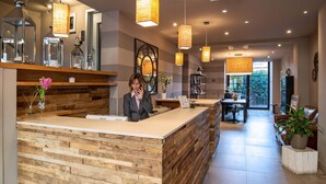 A reception area with a wooden reception desk, pendant lighting, and a view of the dining area with a balcony. - Hotel Orcagna (Florence)