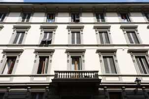 A multi-story building with a symmetrical facade, evenly spaced windows, and a central balcony with a balustrade.