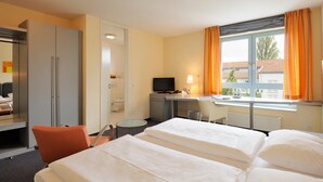 A hotel room with two beds, a desk, a television, and a window with curtains. -  Werkhof Hotel (Hannover)