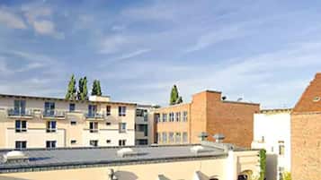 A multi-story building with a flat roof, several windows, and a courtyard with a few trees.