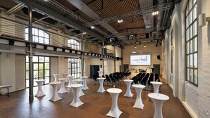 A spacious hall with high ceilings, large windows, and rows of white round tables. -  Werkhof Hotel (Hannover)