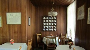 Un espace repas avec des murs en bois, un lustre et une collection d’assiettes décoratives accrochées au mur.