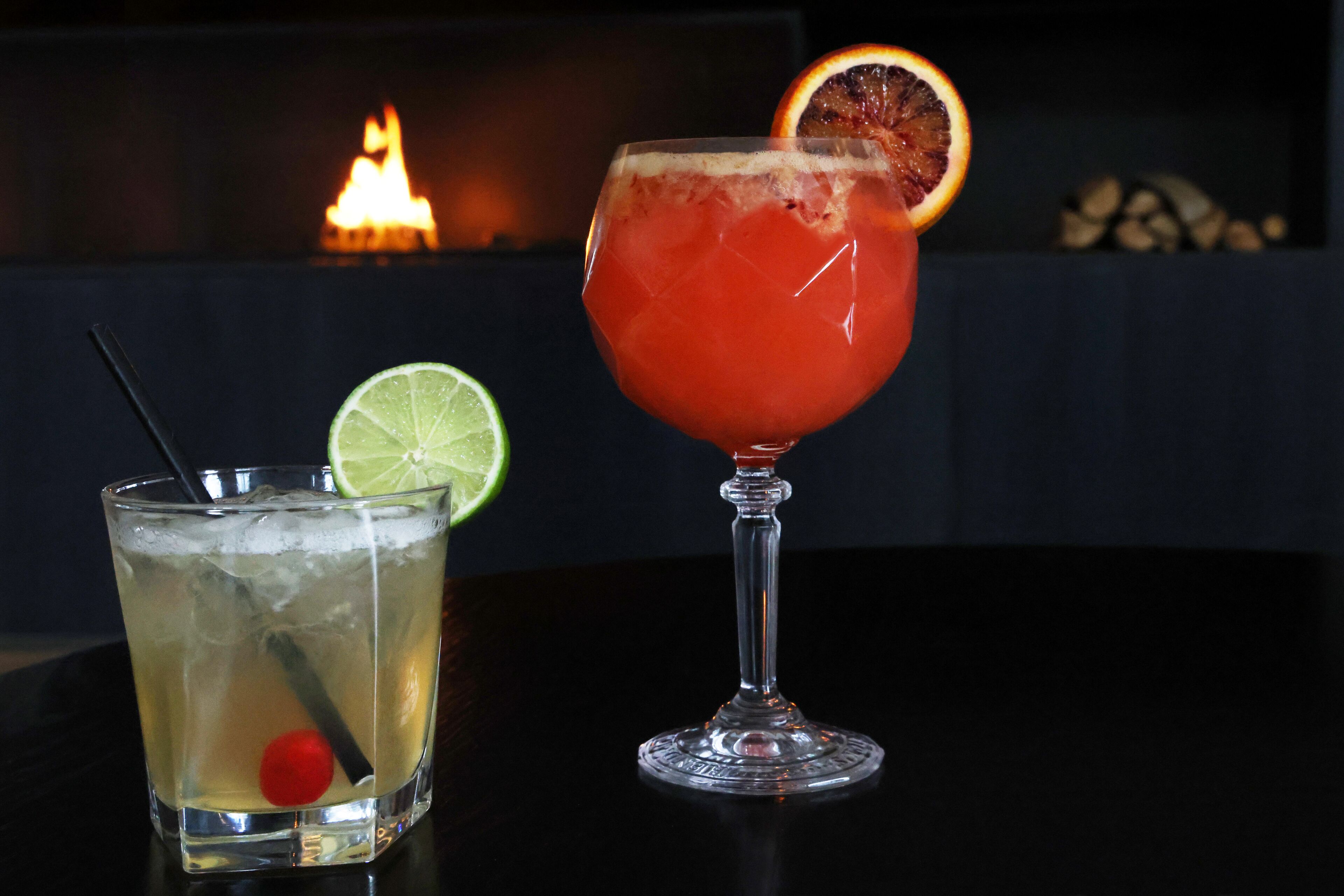 Due cocktail su un tavolo, con un caminetto sullo sfondo.