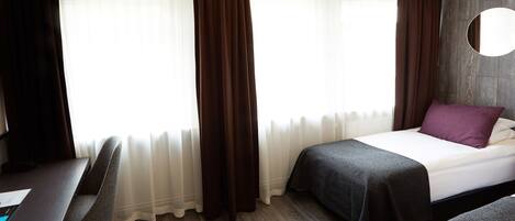 A hotel room with a bed, two bedside tables, a desk, and a chair.