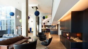 A modern lounge area with leather sofas, black chairs, a coffee table, and a fireplace with logs. - Fosshotel Husavik (Husavik)