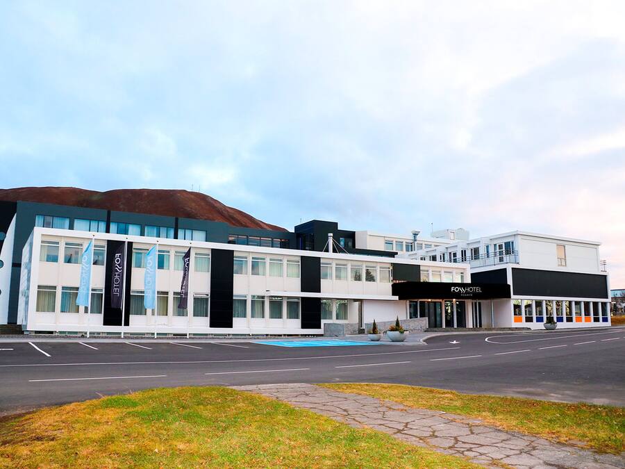 Un hôtel moderne doté d’un toit plat, de grandes fenêtres et d’un espace piscine extérieur bien visible.