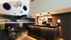 A modern bar area with a counter, seating, and a decorative wall. - Fosshotel Husavik (Husavik)