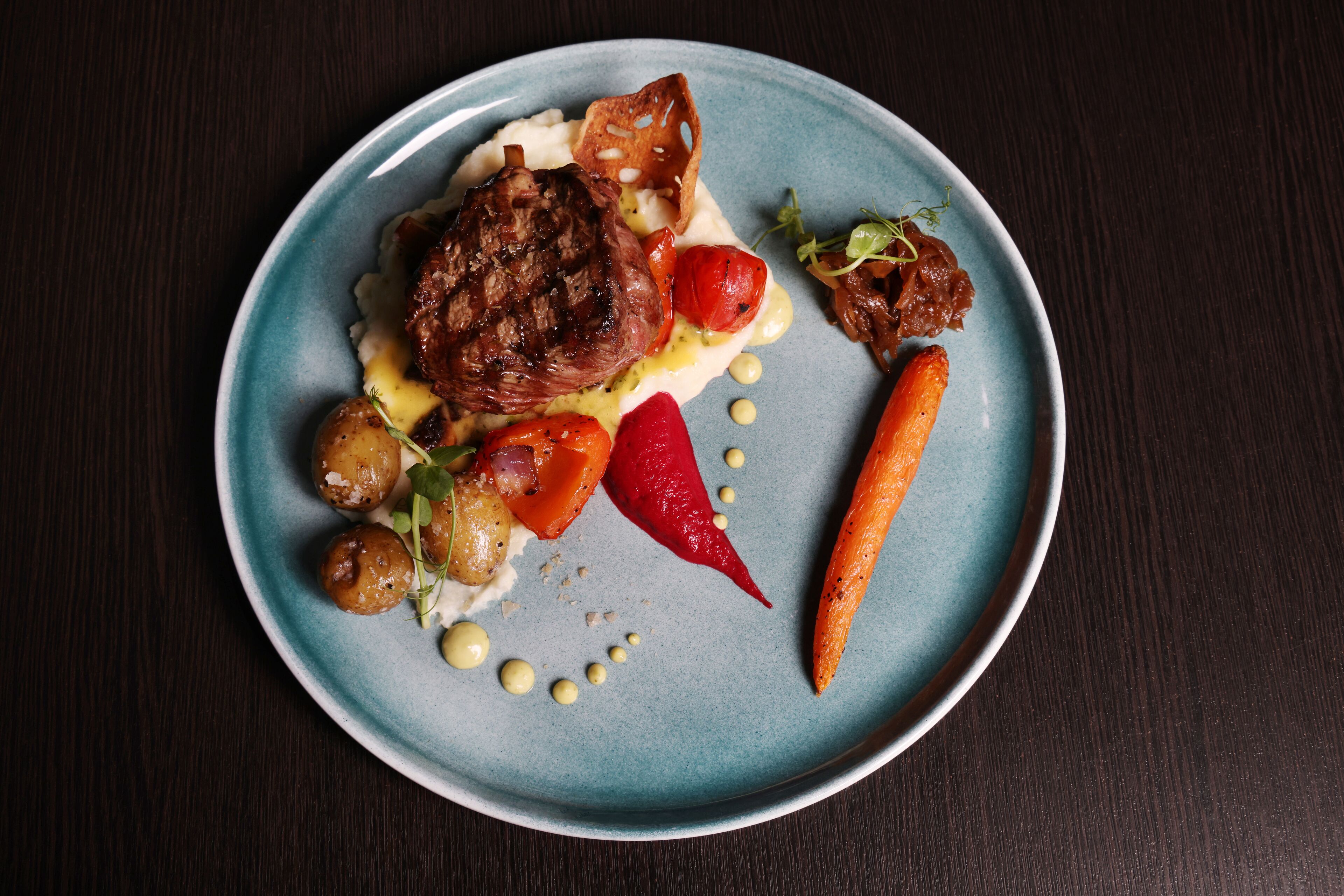 Une assiette contenant un steak, des légumes et de la sauce.