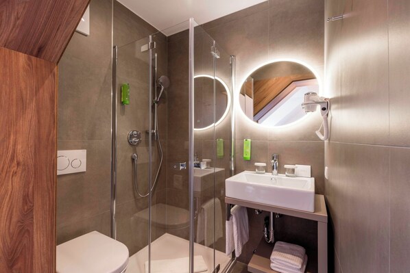 A modern bathroom with a glass-enclosed shower, a sink with a mirror, and a toilet.