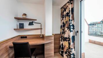 Een moderne kamer met een houten bureau, een zwarte stoel, een lamp en een kamerkleed.