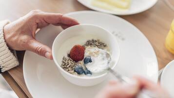A bowl of cereal with strawberries and blueberries on a white plate.