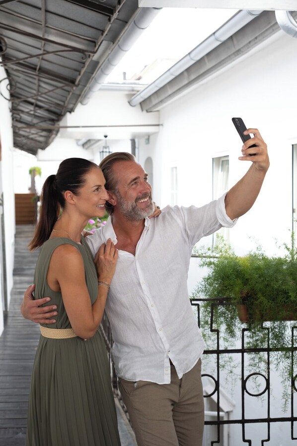 A couple taking a selfie on a balcony with a white building in the background.