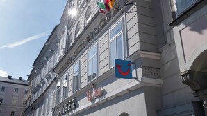 A hotel with a sign reading 'Hotel Wolfsinger,' featuring a traditional European architectural style with arched windows and a stone facade.
