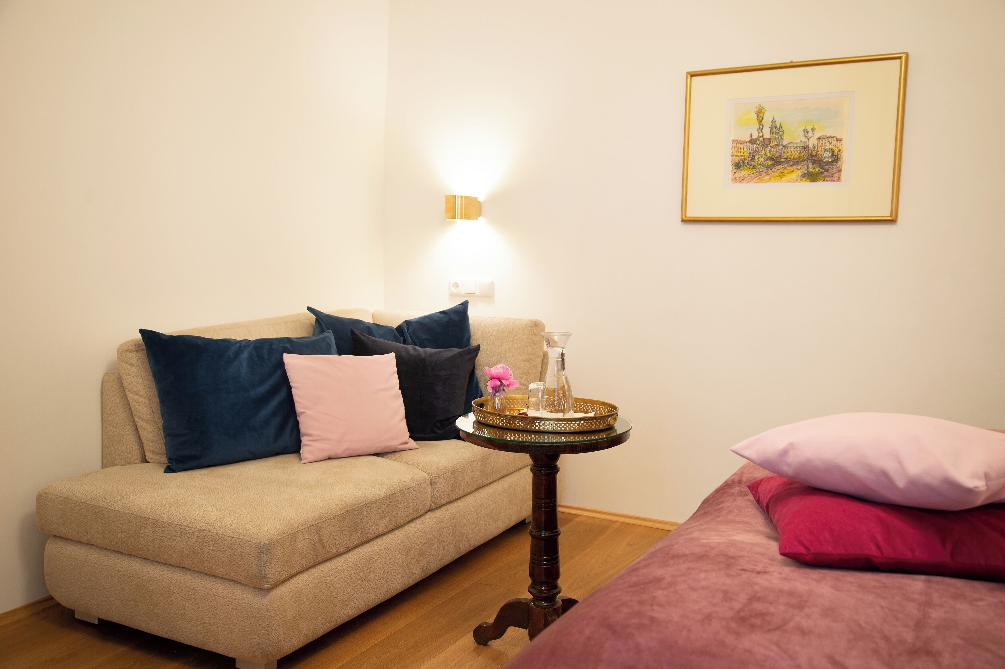 A cozy living room with a beige sofa, a small round table with a tray, and a framed picture on the wall.