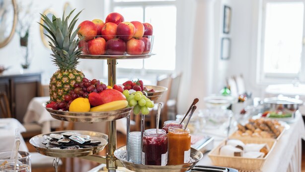 A breakfast buffet with fruits, jams, and pastries.