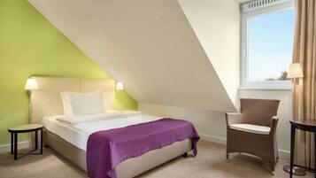 Ein Schlafzimmer mit Bett, Stuhl, Tisch und Fenster.