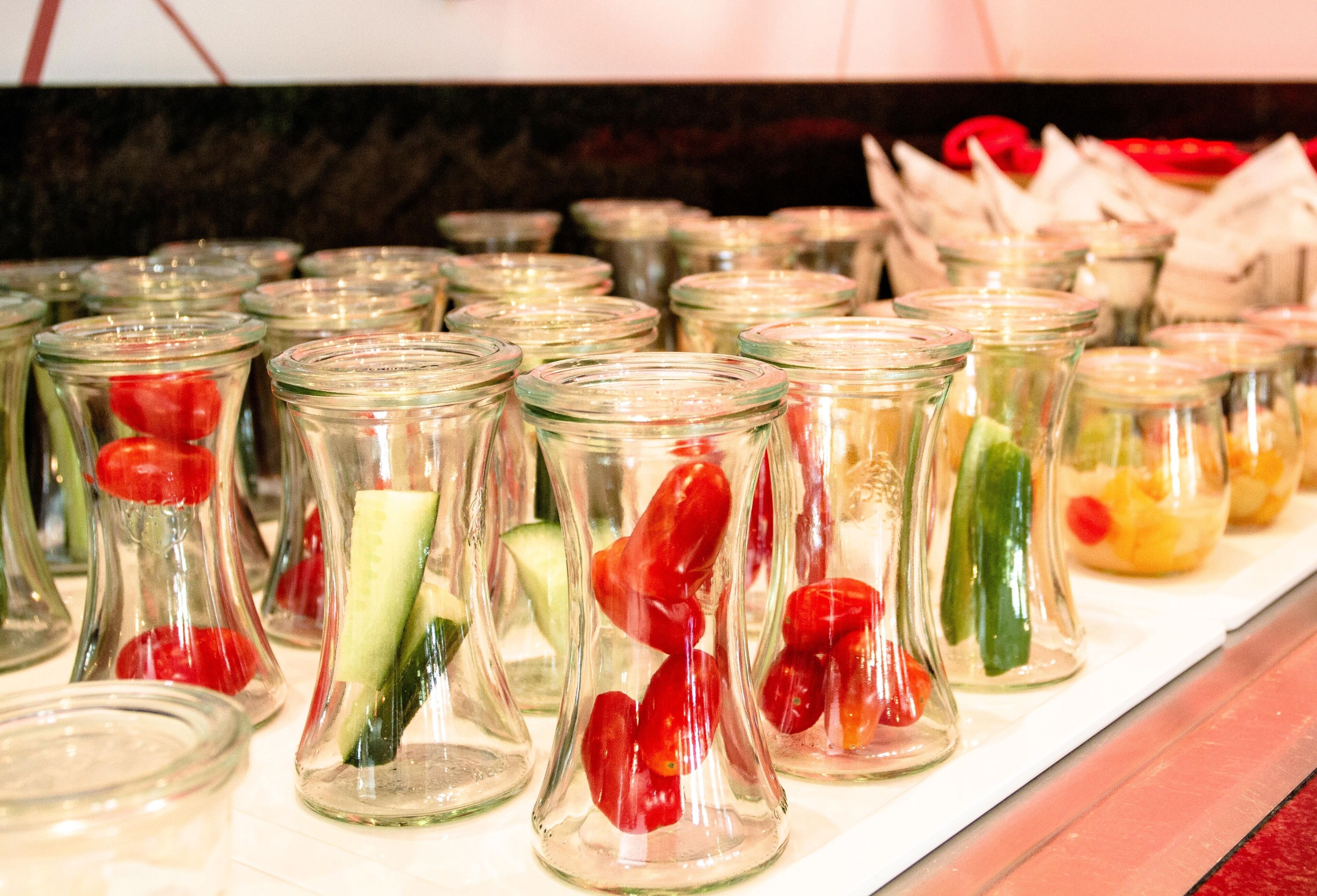 A display of glass jars containing various vegetables.