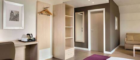 A modern hotel room with a bed, a desk, a wardrobe, and a sofa.