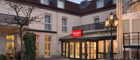 A building with a sign reading "RAMADA BY WIDORAN" and a covered entrance area.