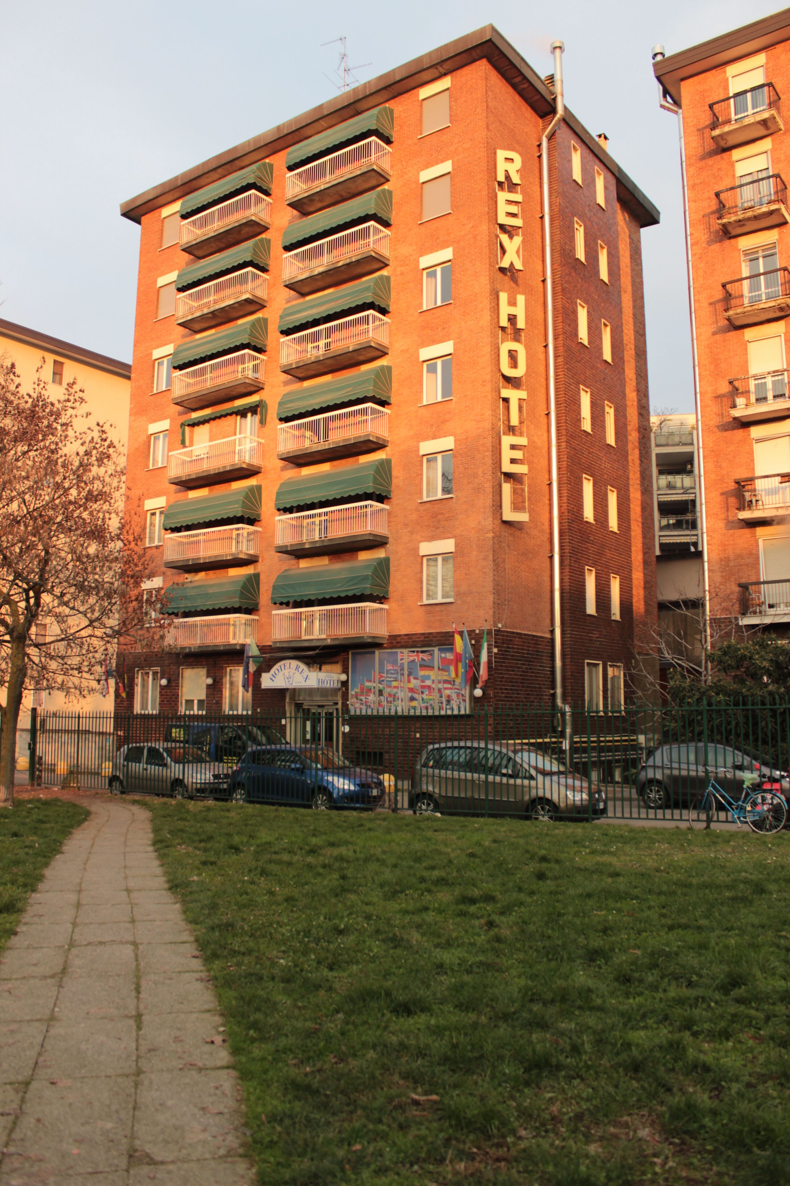 A multi-story hotel with balconies, a visible entrance, and a pathway leading to the entrance.