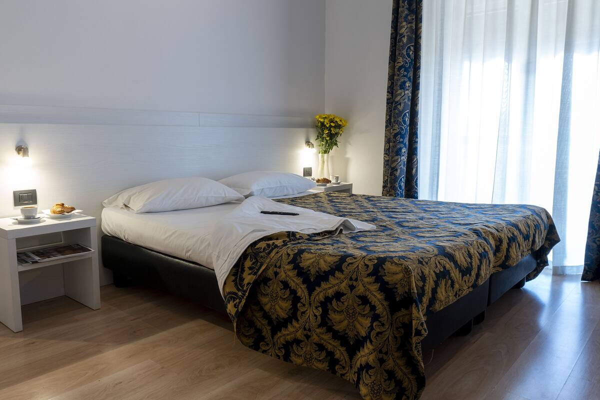 A neatly arranged bedroom with a bed, bedside tables, and a nightstand.