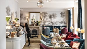 A luxurious living room with a fireplace, a coffee table, and a sofa. - Odéon Hôtel  (Paris)