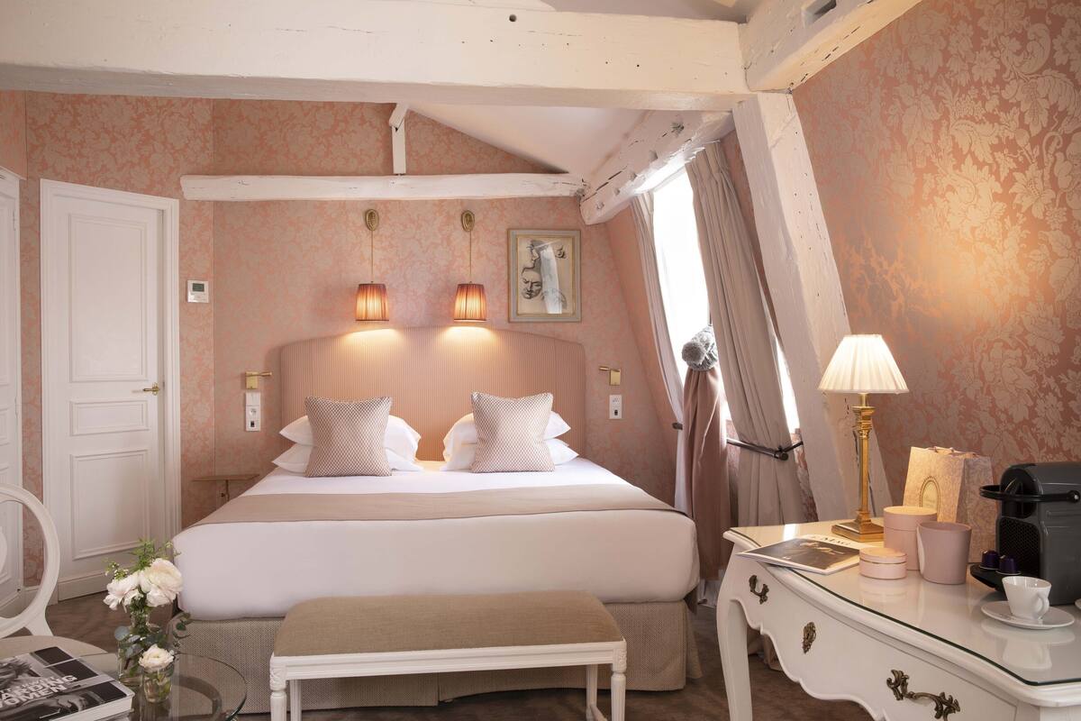 A neatly arranged hotel room with a bed, bedside table, lamp, and a small table with a vase of flowers.