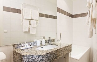 A bathroom with a granite sink, white toilet, and a towel rack with multiple towels.