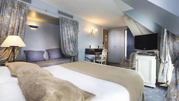 A hotel room with a large bed, a desk, a television, and a chair.