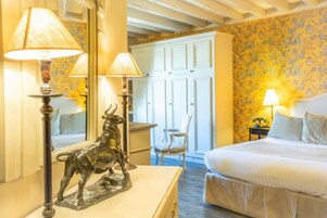 Una camera da letto con un letto, due lampade, una statua decorativa di un toro, una sedia e un armadio.