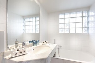 Une salle de bain moderne avec un grand miroir, une baignoire et un meuble-lavabo.