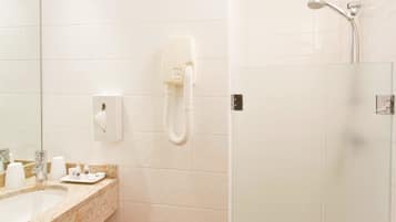 Un baño con lavamanos, espejo y ducha con cabezal de ducha manual.